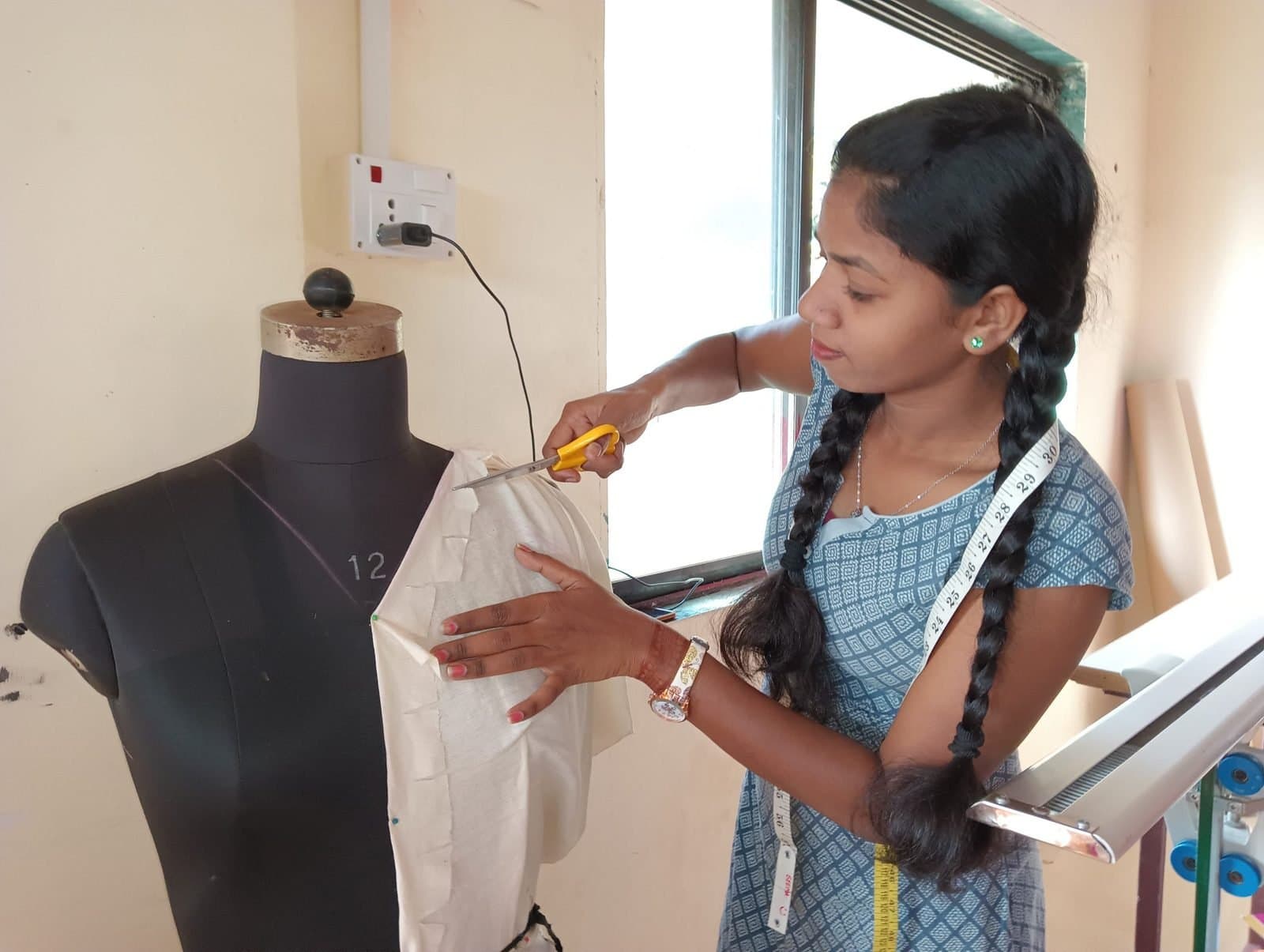 A design student draping and cutting fabric on a dress form