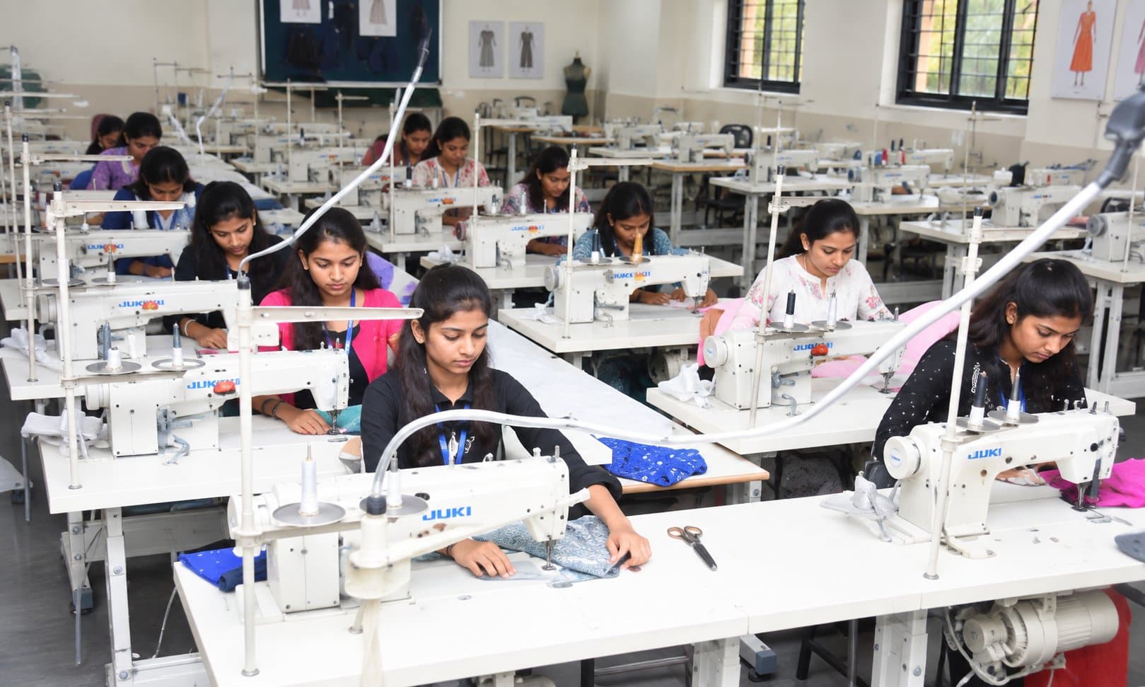 Design students stitching at industrial sewing machines in the garment workshop