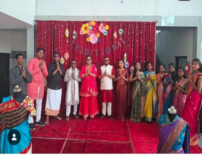 Students and staff in traditional dress in front of a decorated backdrop