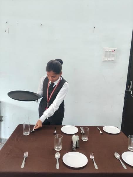 A student laying a table during a food and beverage service practical