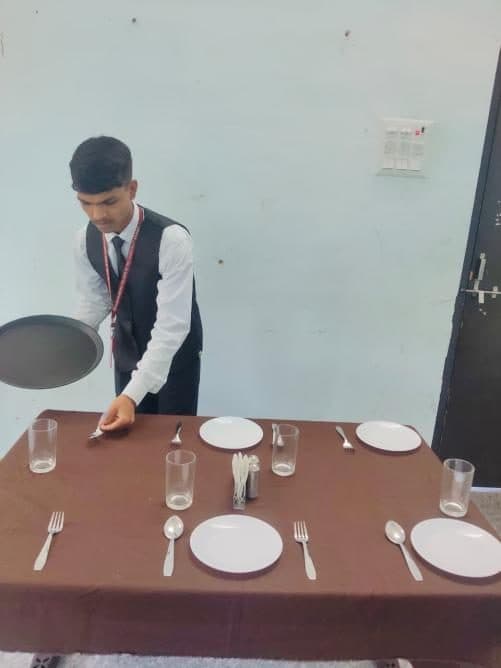 A student placing a glass during a food and beverage service practical