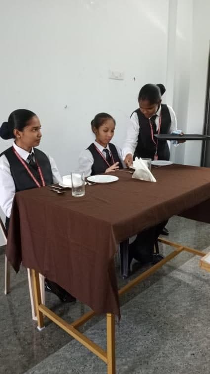 Students serving at a laid table during a service practical