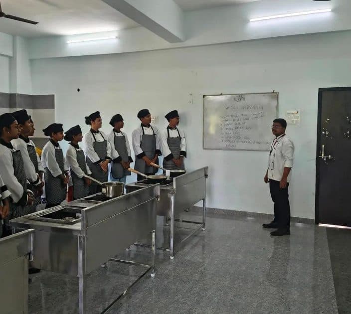 Students in chef uniforms at the ranges during a kitchen practical