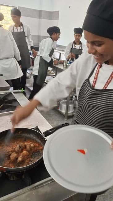A student cooking in a pan during a kitchen practical