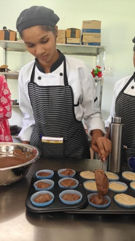 A student filling a muffin tray in a bakery practical