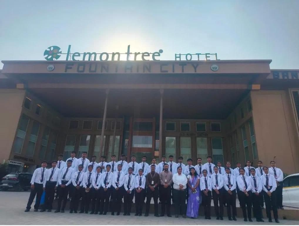 Hospitality students in front of a Lemon Tree hotel on an industrial visit