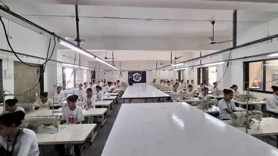 Rows of sewing machines with students at work in the Garment Construction Lab