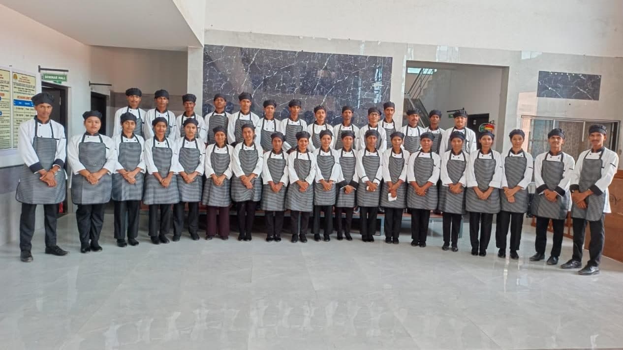Hospitality students in chef uniforms lined up in the training kitchen